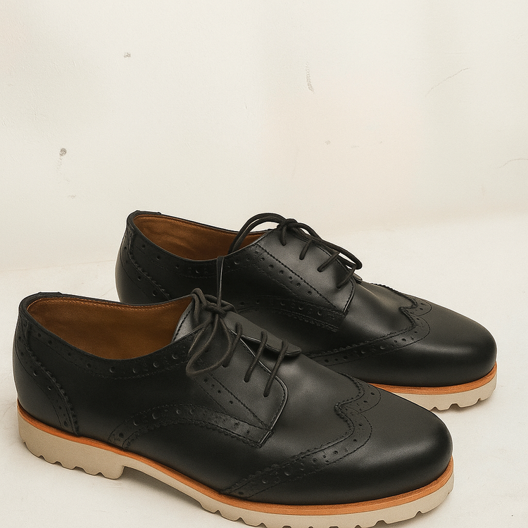 Pair of black leather shoes with brown soles on a white background