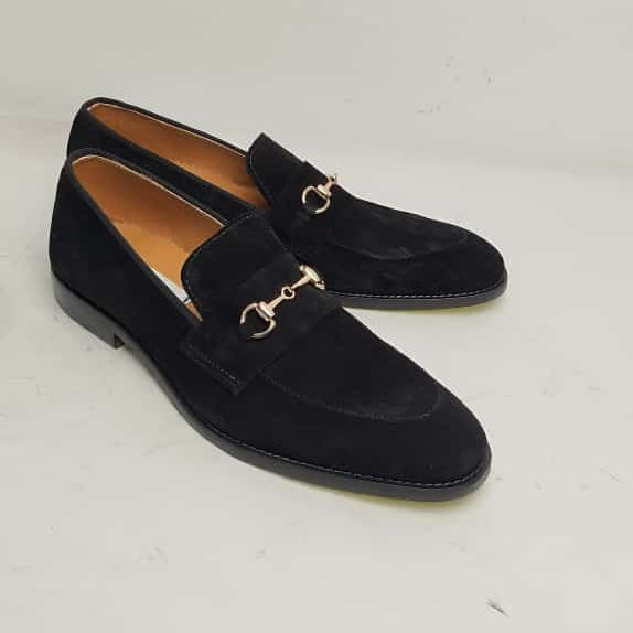 A pair of black suede loafers with a gold horsebit detail on the vamp, displayed against a white background.