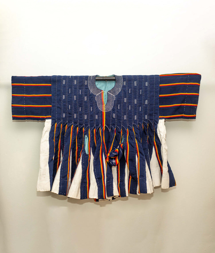 A traditional hand-sewn smock with a pattern of blue, white, and red stripes.