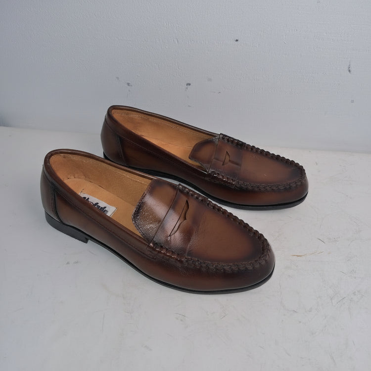 Pair of brown loafers on a white surface with a light gray background
