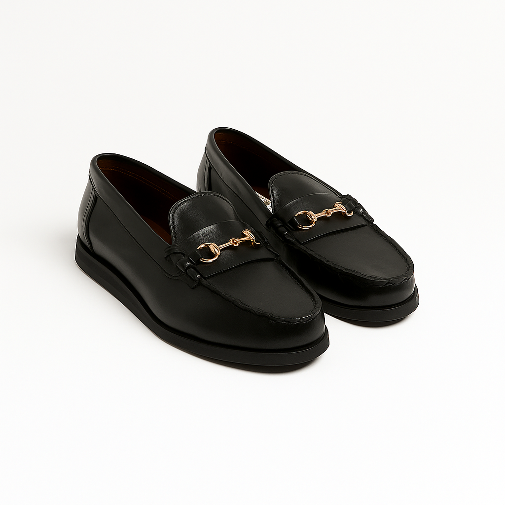 Black loafers with gold accents on a white background