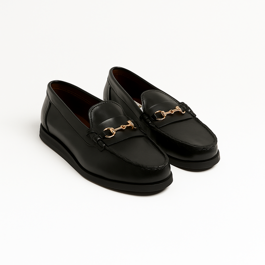 Black loafers with gold accents on a white background