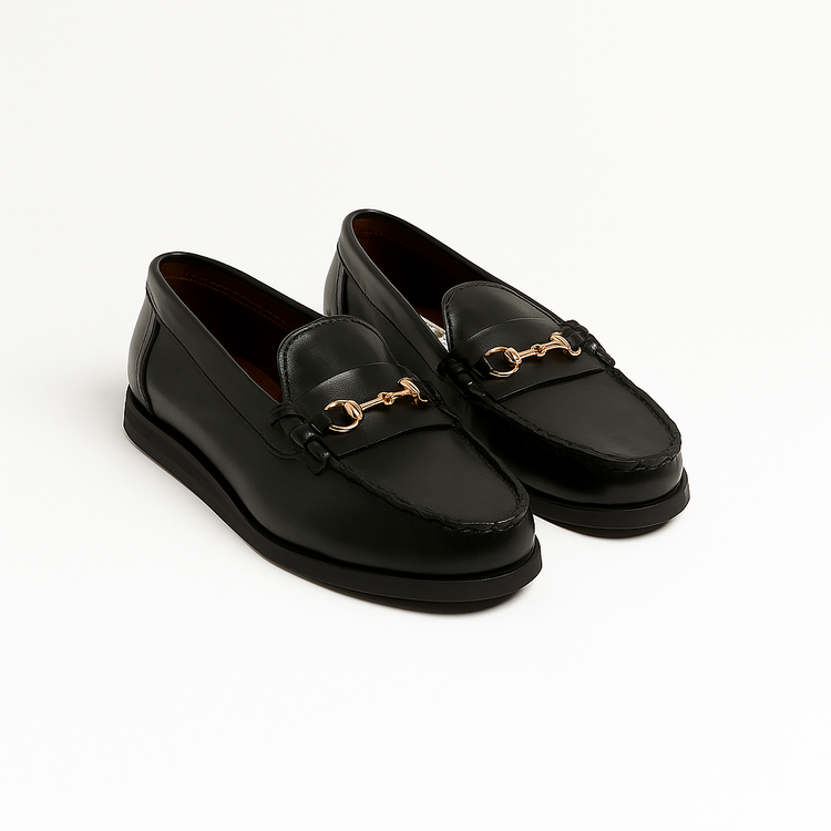 Black loafers with gold accents on a white background