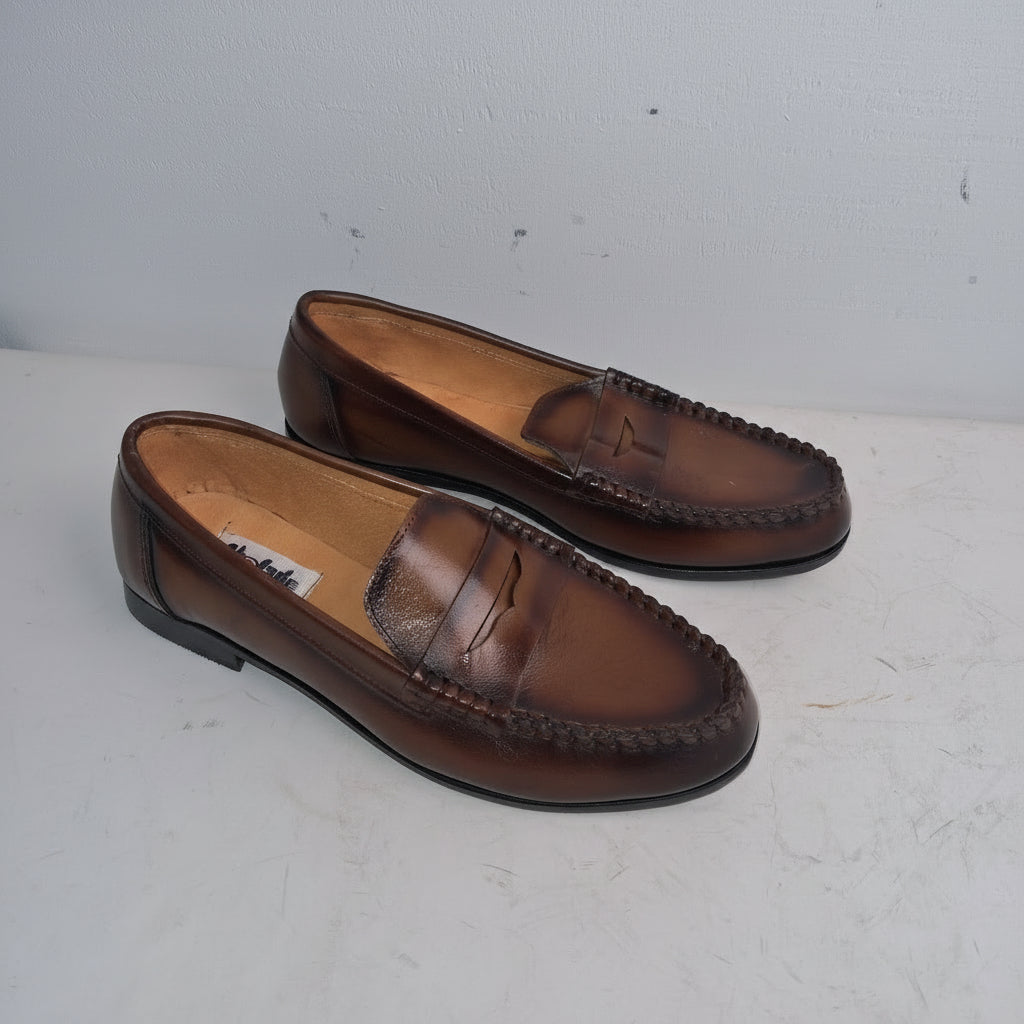 Pair of brown loafers on a white surface with a light gray background